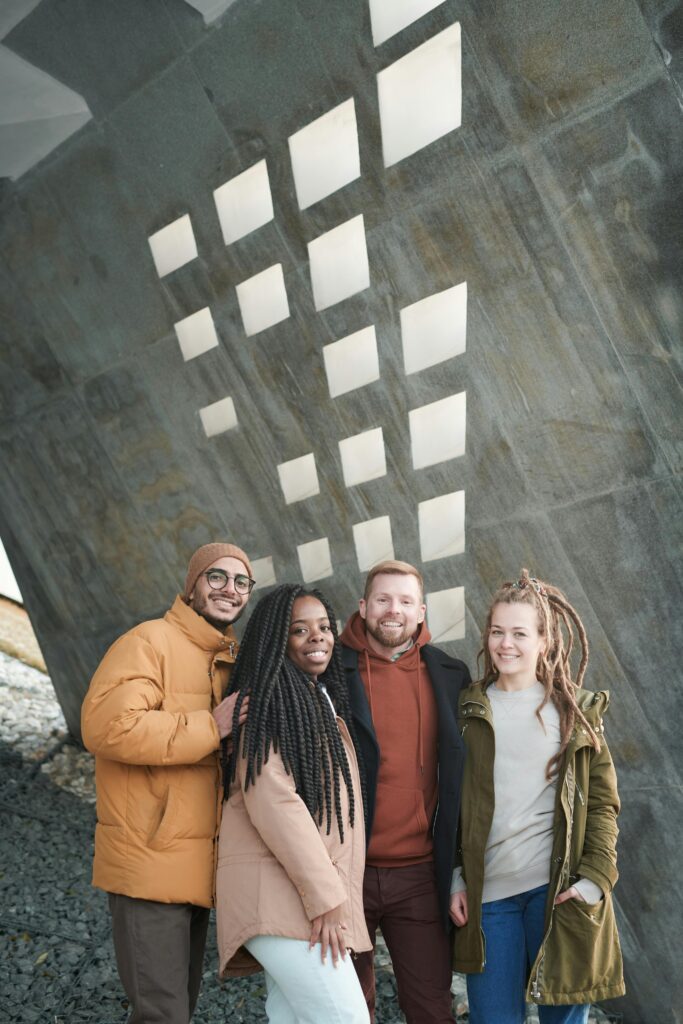 Four diverse friends smiling in an urban setting under geometric patterns.